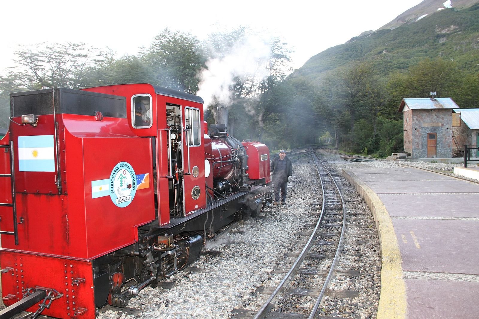 Trem do Fim do Mundo: locomotiva a vapor vermelha soltando fumaça na estação, em Ushuaia